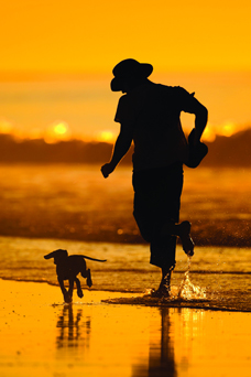 Pet owner running with dog along a shoreline